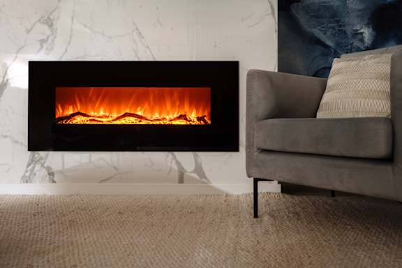 A modern fireplace with a grey couch in front of it.
