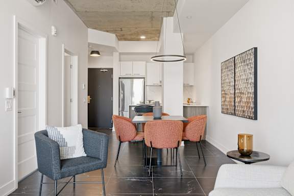 A modern living room with a grey sofa, orange chairs and a black and white painting on the wall.
