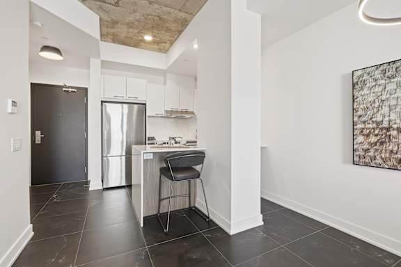 A kitchen with a black chair and a black fridge.