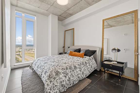 A bedroom with a large bed and a view of the beach through the window.