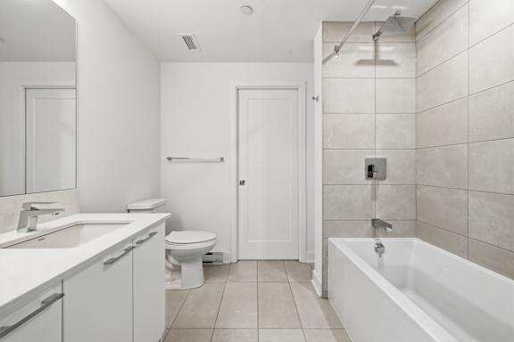 A white bathroom with a toilet, sink, and bathtub. at Château golf, Gatineau, J9H 0M9