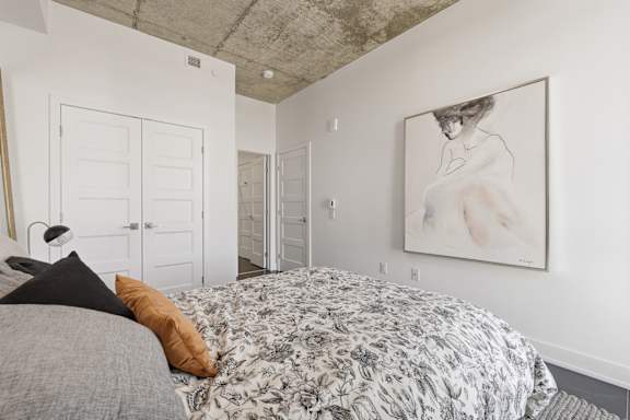 A bedroom with a large bed and a painting on the wall.
