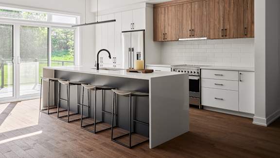 A kitchen with a white counter top and a row of black bar stools.
