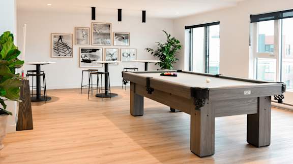 A pool table is in the middle of a room with a plant and a picture frame on the wall. at Château golf, Gatineau, J9H 0M9