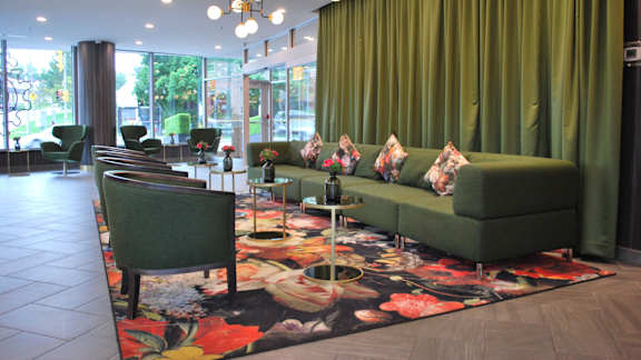 A living room with a green couch and a floral rug.