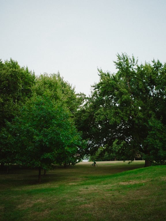 A person is walking on a grassy field with a building in the background.