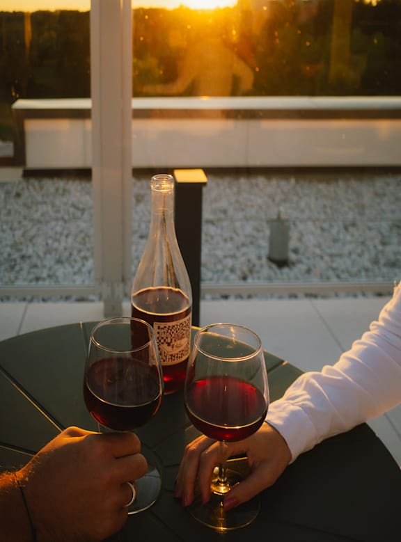 Two people sitting at a table on a balcony during sunset.