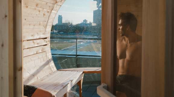 A man stands in front of a window looking out at a cityscape at The Dale Apartments , Ontario