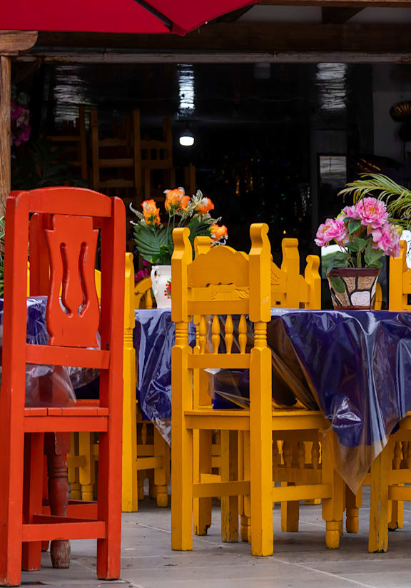 A group of people are sitting at tables under red umbrellas.
