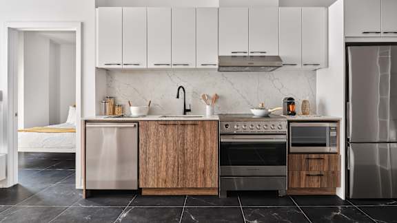 A modern kitchen with a marble backsplash and wooden cabinets. at Le ColumbiaApartments , Gatineau