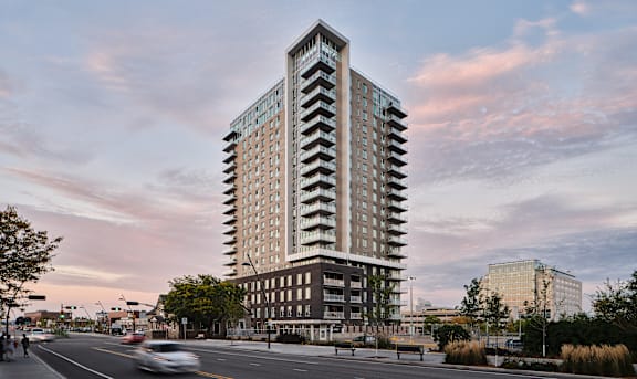 A tall building with a lot of windows is in the middle of a street.