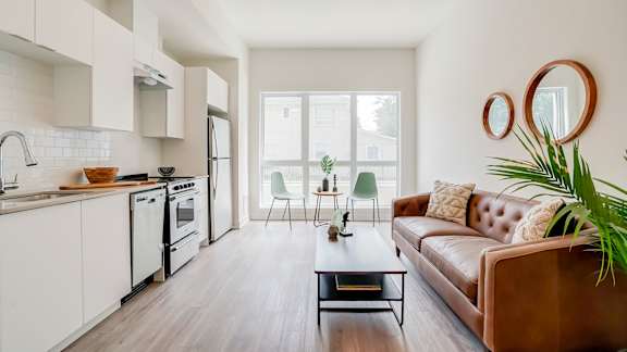A modern kitchen with a brown leather couch and a wooden floor.