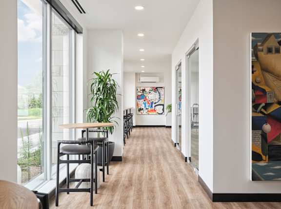 A long hallway with a table and chairs on the left and a painting on the right at The Dale Apartments , Ontario, K1Y 4Y5