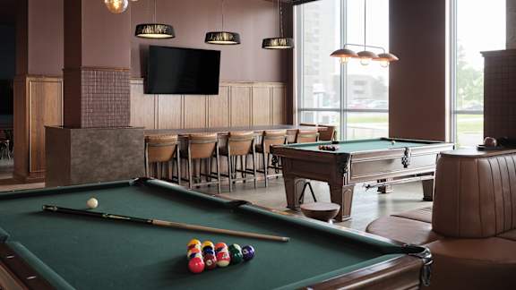 A pool table with a billiard ball and cue sticks on it.