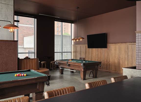 A pool table with a green cloth and a television mounted on the wall at The Dale Apartments , Ottawa, ON