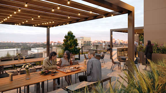 People are sitting at tables under a wooden canopy.