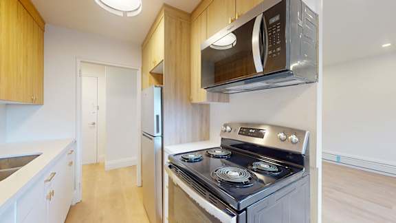 A kitchen with a stove, refrigerator, and microwave.