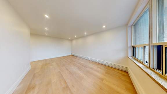 A room with wooden floors and a window on the right side.