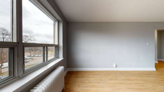 A room with a large window and a radiator on the wall.