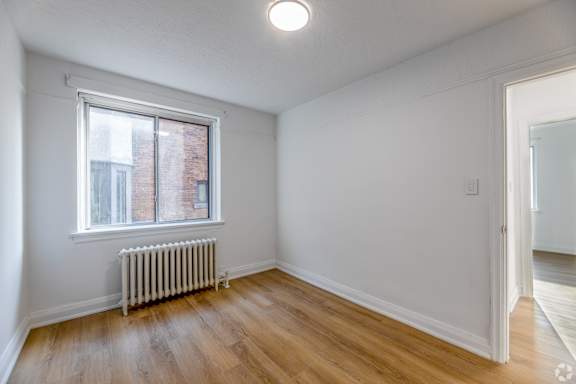 A room with a window and a radiator on the floor.