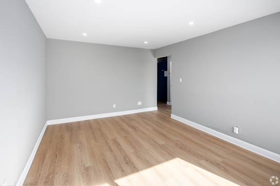 A room with wooden flooring and a door in the background.