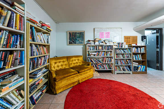 A room with a yellow sofa and bookshelves filled with books.