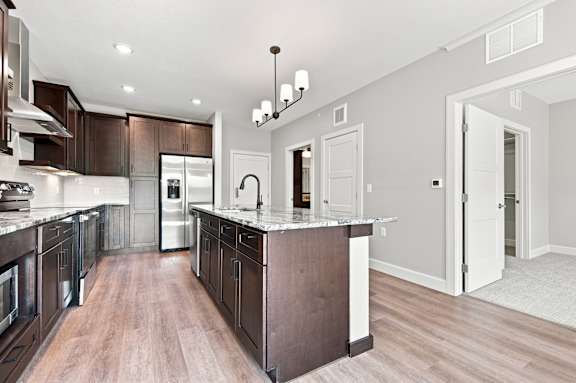 A modern kitchen with dark wood cabinets and a white island.