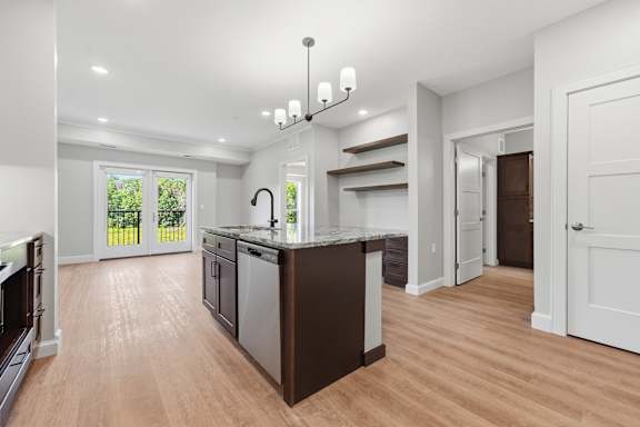 A kitchen with a black island and wooden floors.