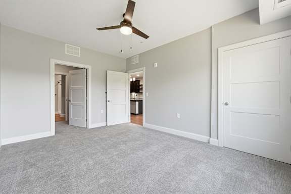 A room with a ceiling fan and carpeted floor.