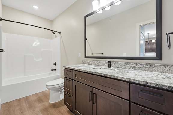 A bathroom with a marble countertop and a large mirror.