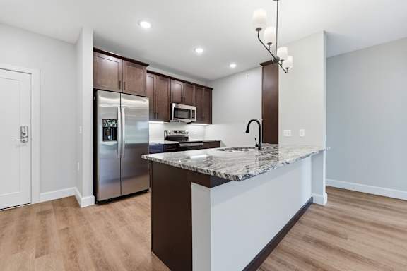 A kitchen with a marble countertop and stainless steel appliances.