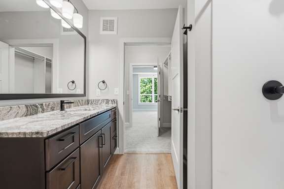 A bathroom with a marble countertop and a large mirror.