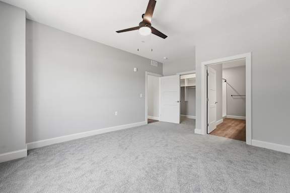 A room with a ceiling fan and carpeted floor.