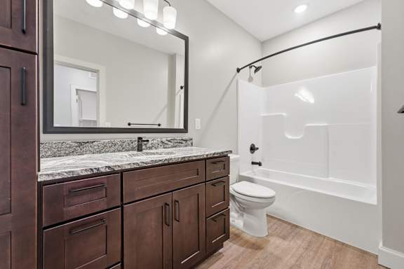 A bathroom with a marble countertop and a large mirror.