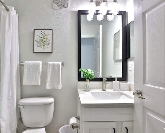 A white bathroom with a toilet, sink, mirror, and towel.
