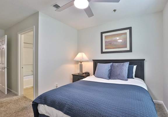 A bedroom with a bed, nightstand, and lamp.