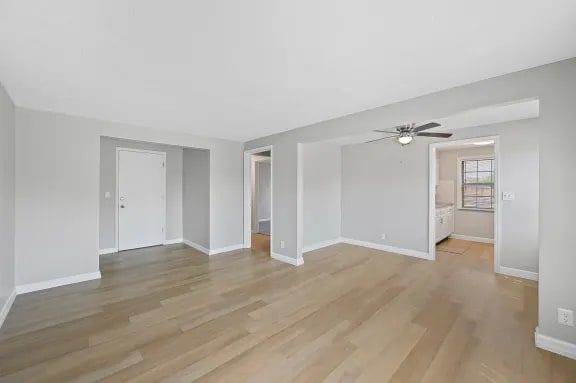 A spacious room with wooden flooring and a ceiling fan.