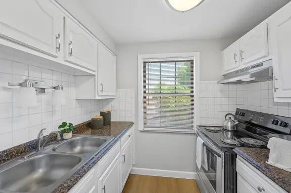 A kitchen with white cabinets and a granite countertop.