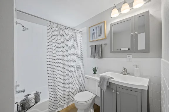A white bathroom with a toilet, sink, and shower.