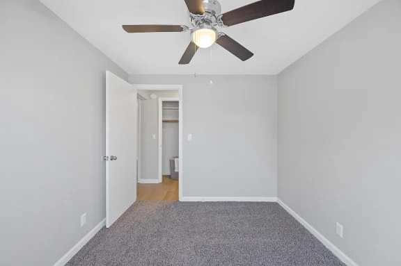 A room with a ceiling fan and carpeted floor.