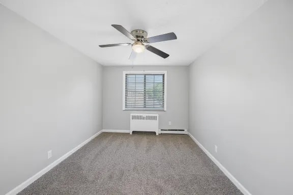A room with a ceiling fan and a window with blinds.