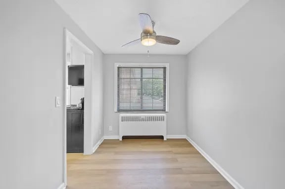 A room with a ceiling fan and a window with blinds.