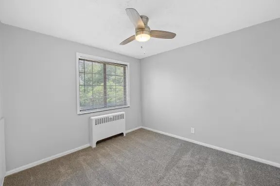 A room with a ceiling fan and a window with blinds.