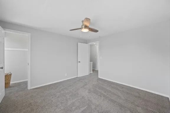 A room with a ceiling fan and carpeted floor.