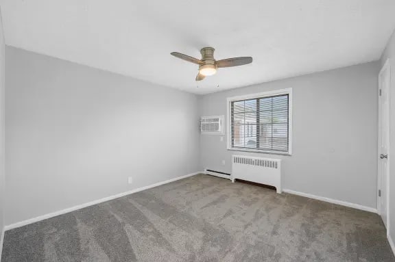 A room with a ceiling fan and a window with blinds.