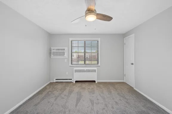 A room with a ceiling fan and a window with blinds.