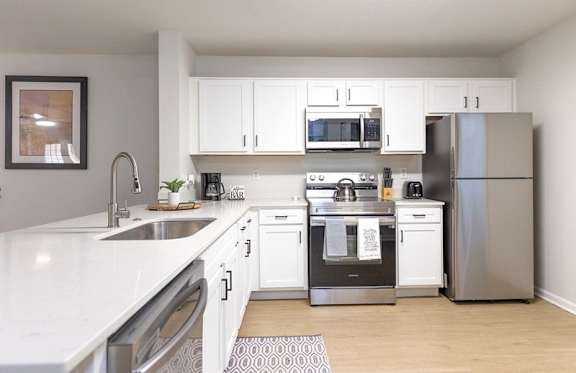 A modern kitchen with white cabinets and stainless steel appliances.