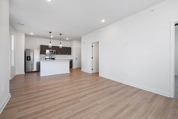A spacious living room with a kitchen in the background.
