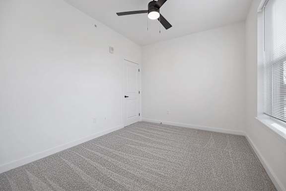 A room with a ceiling fan and carpeted floor.
