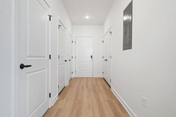 A long hallway with white doors and wood floors.